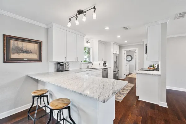 a kitchen with granite countertop white cabinets and chairs