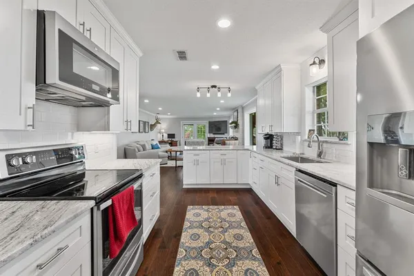 a large kitchen with stainless steel appliances granite countertop a stove a sink dishwasher and cabinets with wooden floor