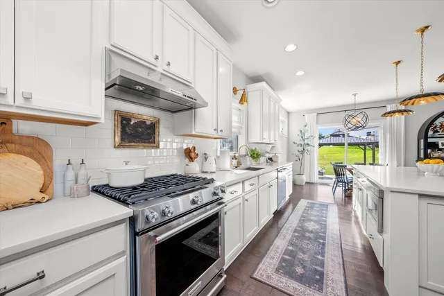a kitchen with stainless steel appliances granite countertop a sink a stove and a wooden floors