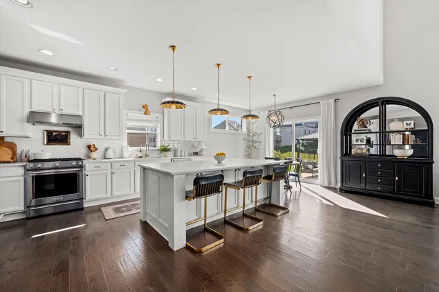 a kitchen with stainless steel appliances a white stove top oven a sink dishwasher and white cabinets with wooden floor