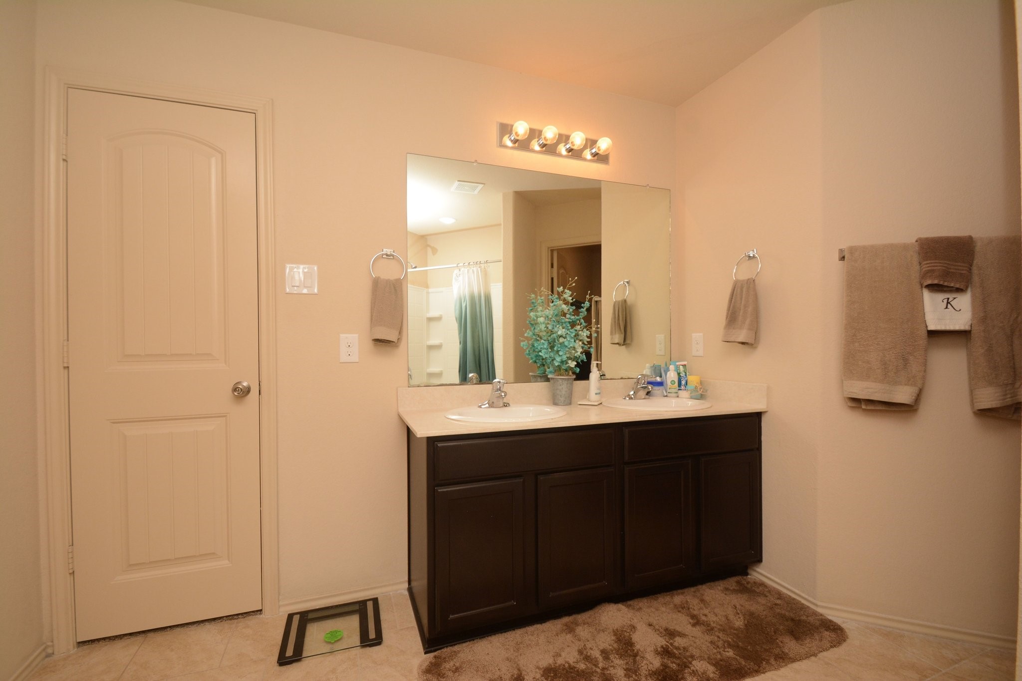 23318 Dukes Run Drive Spring, TX 77373 - Photo 33 of 41 This bathroom features a spacious vanity with dual sinks, a large mirror, and ample storage. It has neutral tile flooring, warm lighting, and a cozy, inviting feel.