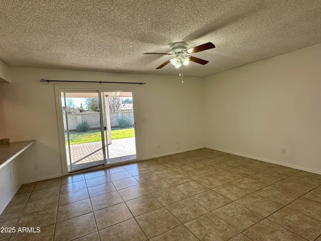 an empty room with windows and chandelier fan