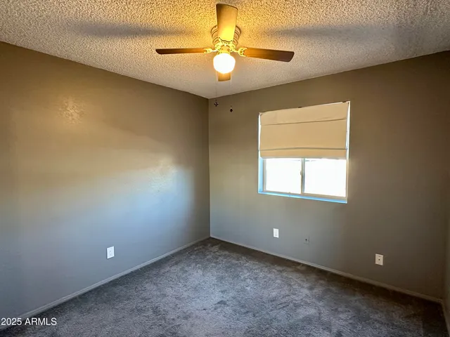 an empty room with a chandelier fan and windows