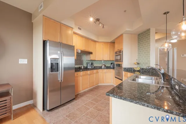 a large kitchen with granite countertop a sink and white cabinets