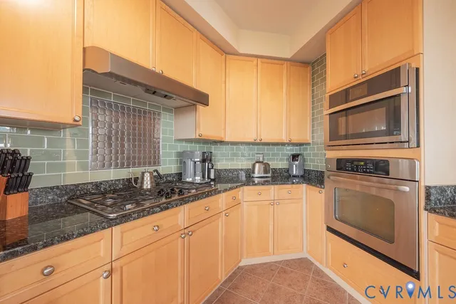 a large kitchen with granite countertop a sink a counter space appliances and cabinets