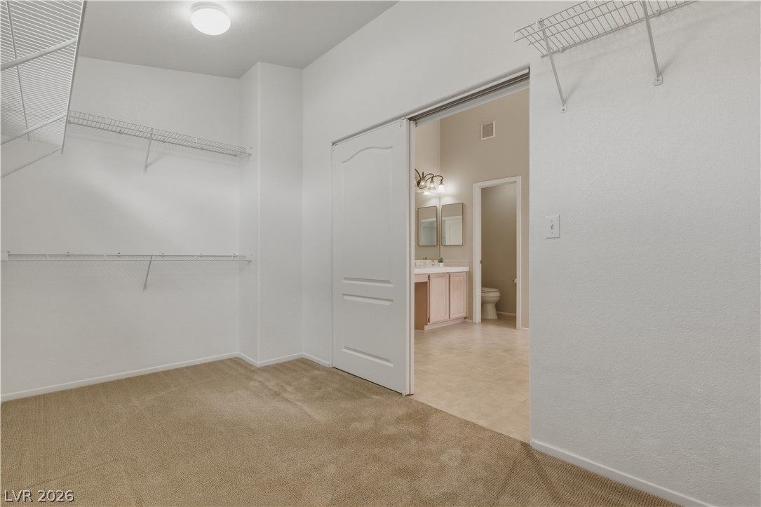29 Olive Tree Henderson, NV 89074 - Photo 37 of 60 This spacious walk-in closet seamlessly connects to a bathroom, offering convenience and organization.