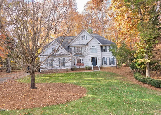a front view of a house with a yard and large trees