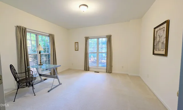 a view of an empty room with furniture and windows