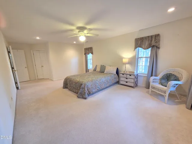 a spacious bedroom with a bed a couch and chandelier