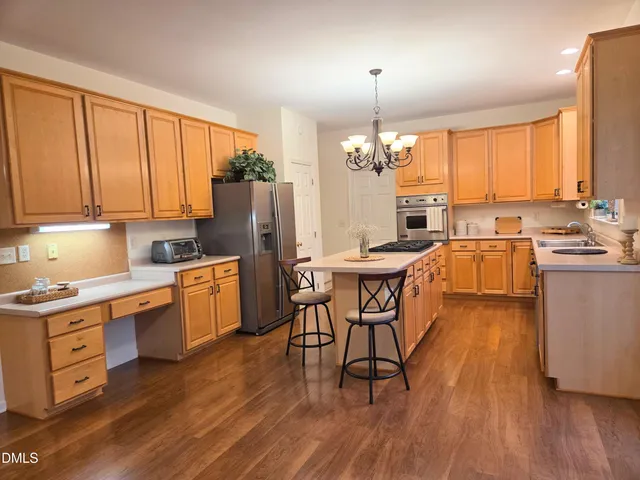 a kitchen with stainless steel appliances kitchen island granite countertop wooden floors and white cabinets