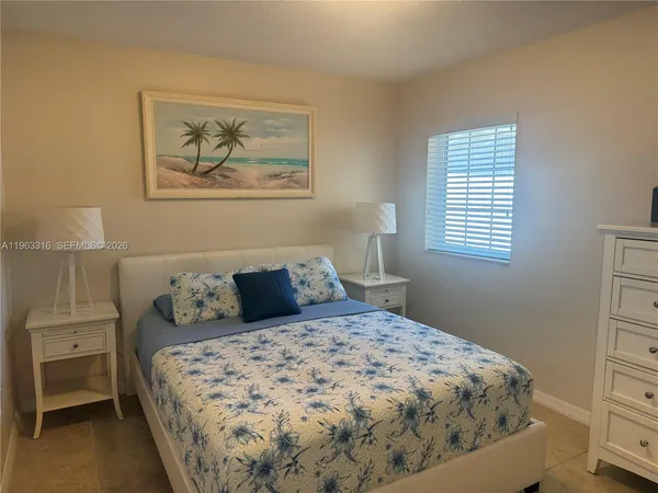 a bedroom with a bed and a lamp on dresser