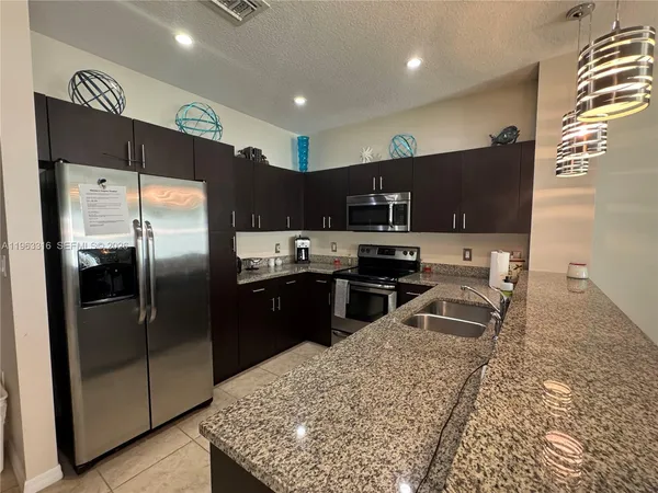 a kitchen with stainless steel appliances granite countertop a refrigerator a stove a sink a microwave and a refrigerator