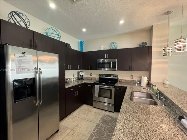 a kitchen with stainless steel appliances granite countertop a refrigerator a sink a stove and oven