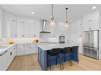 a kitchen with stainless steel appliances granite countertop a sink a stove a refrigerator and white cabinets