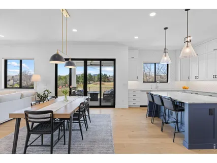 a dining hall with stainless steel appliances kitchen island a table chairs and a kitchen view