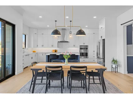 a kitchen with stainless steel appliances kitchen island granite countertop a dining table chairs and white cabinets