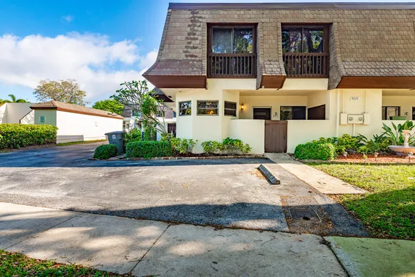 a view of a white building among the street with palm trees