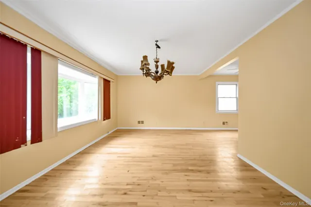 a view of a livingroom with a chandelier windows and wooden floor