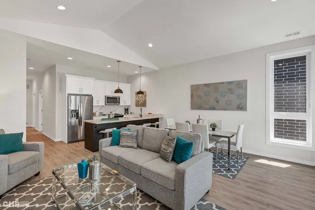 a living room with furniture kitchen view and a wooden floor