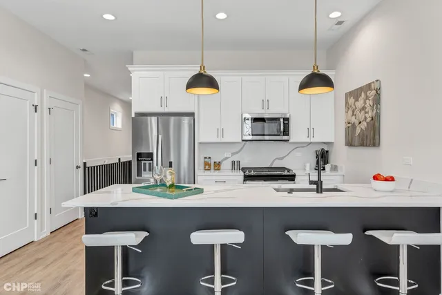 a kitchen with stainless steel appliances a dining table chairs and a refrigerator