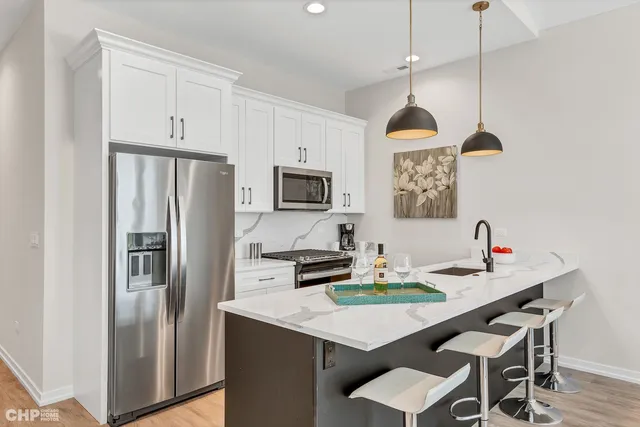 a kitchen with stainless steel appliances a dining table chairs and refrigerator