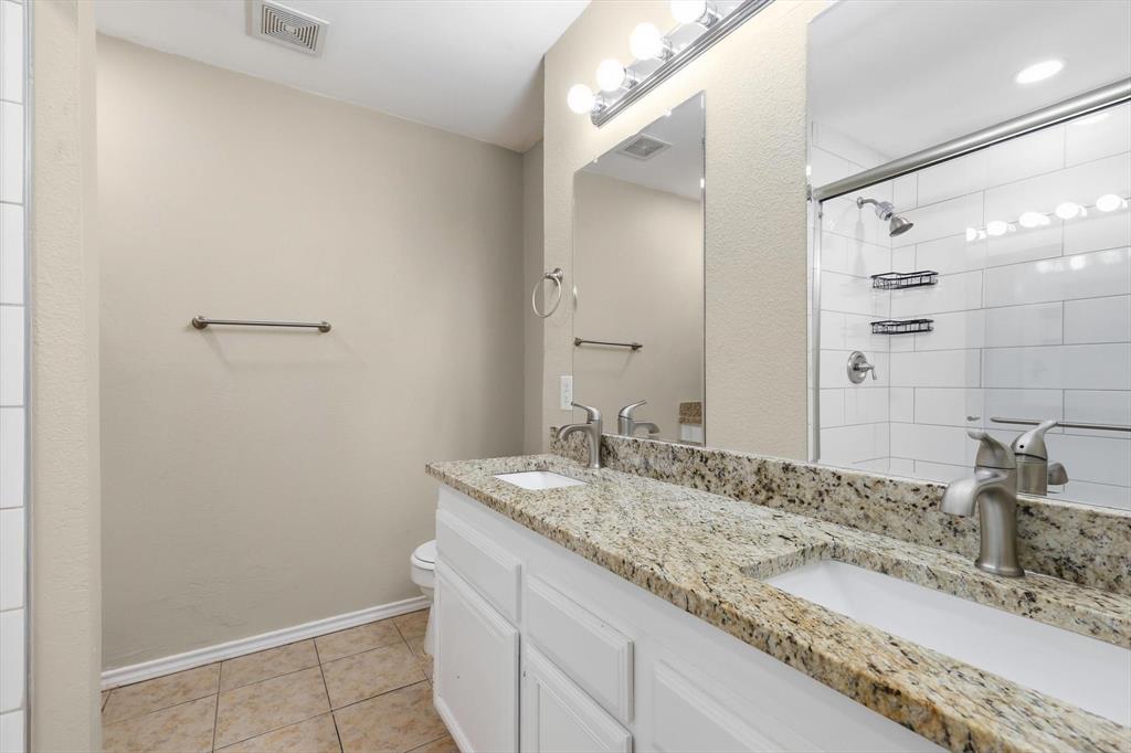 7733 Liz Lane Watauga, TX 76148 - Photo 17 of 27 Full bathroom featuring double vanity, a tile shower, and light tile patterned flooring