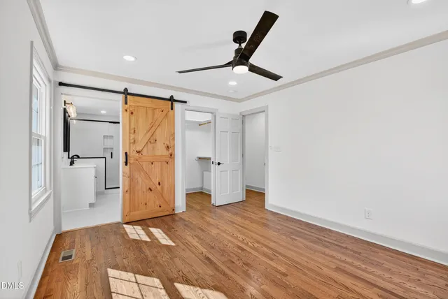 a view of empty room with wooden floor and fan