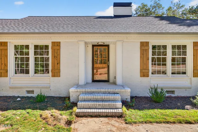 a front view of a house with a garden and tree