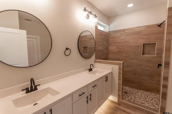 a bathroom with a double vanity sink mirror and shower