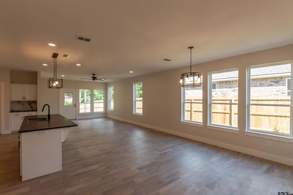 a view of an empty room with window and wooden floor