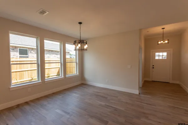 a view of an empty room with window and wooden floor