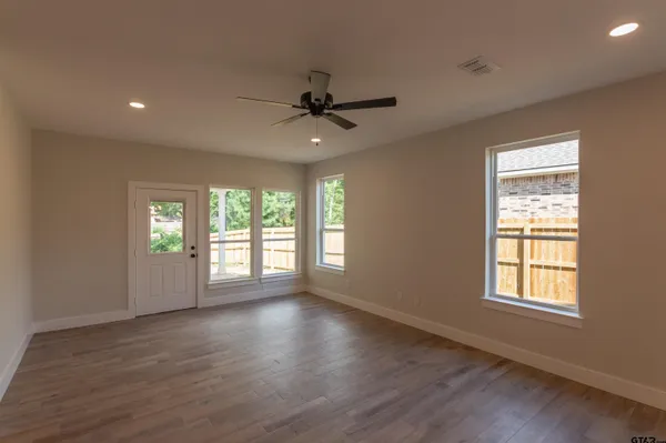 a view of an empty room with a window and wooden floor