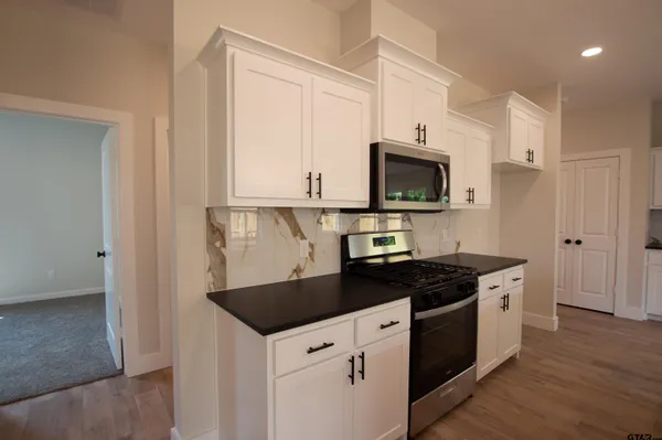 a kitchen with granite countertop white cabinets and black appliances