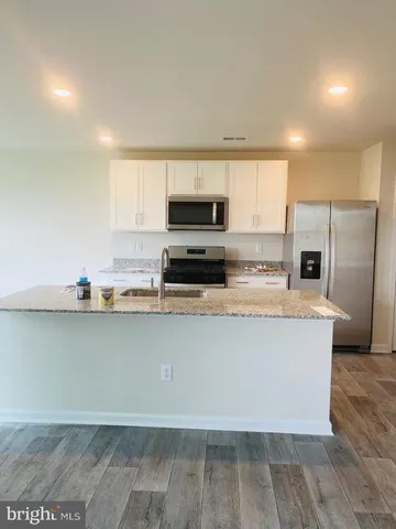 a kitchen with granite countertop a refrigerator a stove a microwave a sink and cabinets