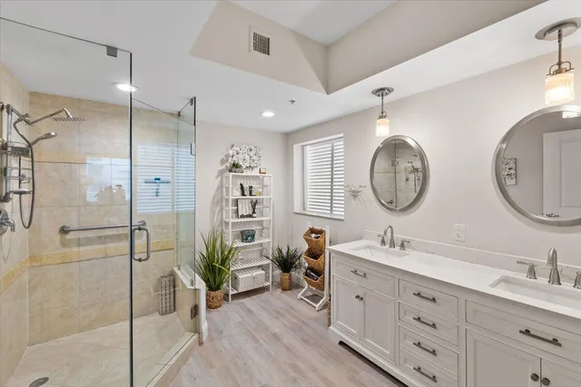 a spacious bathroom with double vanity a glass door shower a mirror and a sink