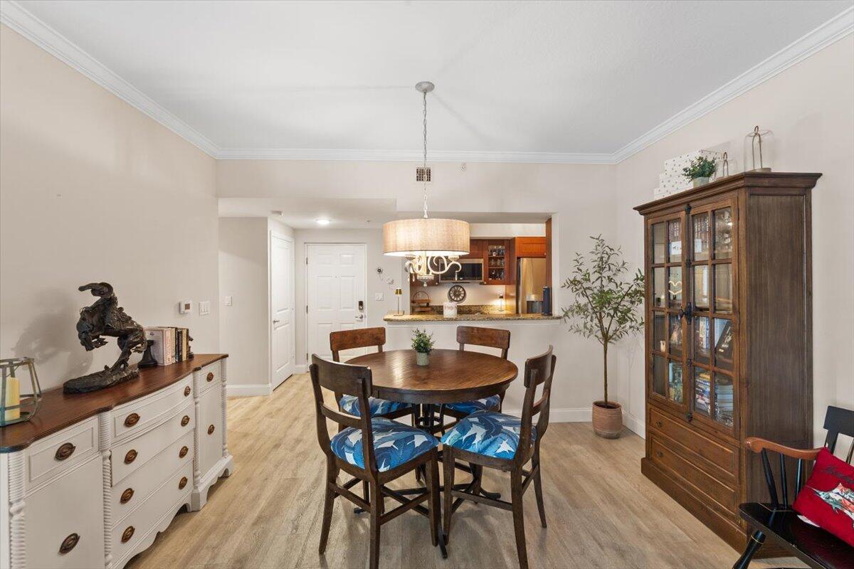 815 Northwest Flagler Avenue, Unit 201 Stuart, FL 34994 - Photo 8 of 43 a dining room with wooden floor a chandelier a wooden table and chairs