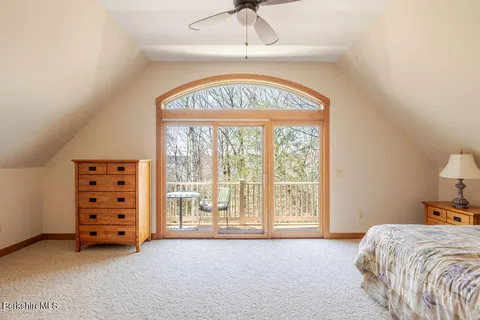 a spacious bedroom with a bed a dresser and a large window