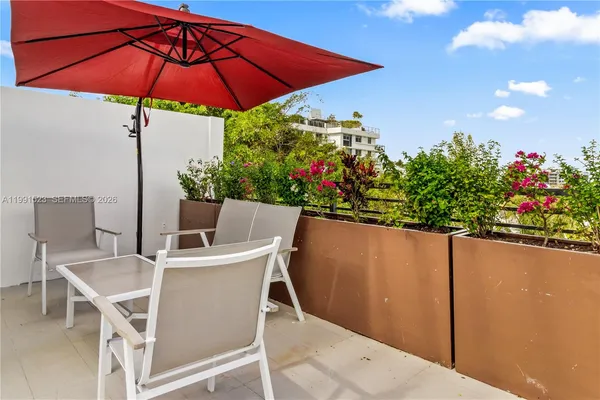 a patio with a table and chairs under an umbrella