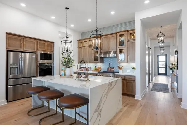 a kitchen with stainless steel appliances granite countertop a refrigerator a sink dishwasher a stove and a refrigerator with wooden floor