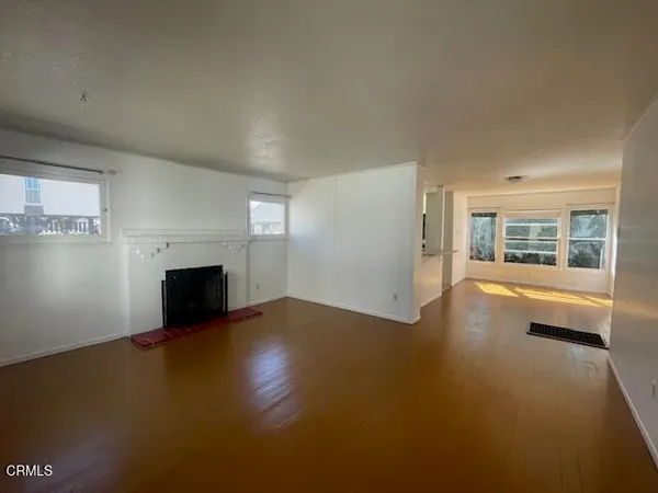 a view of empty room with fireplace and wooden floor