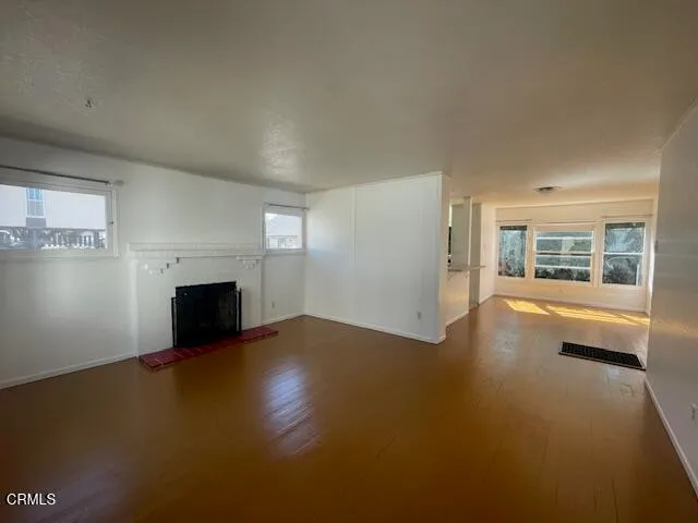 a view of empty room with fireplace and wooden floor