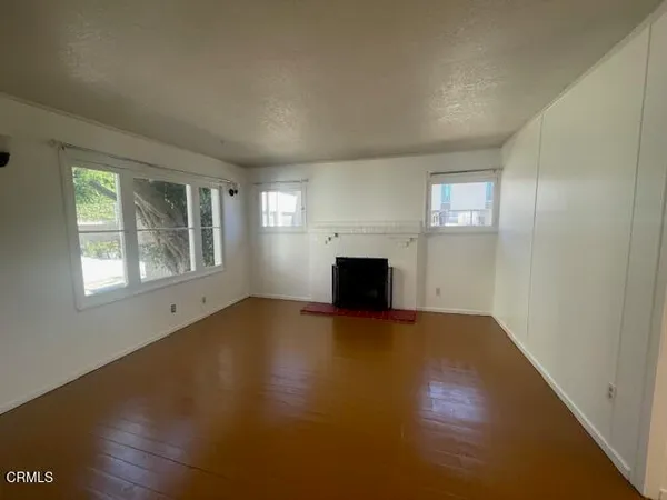 an empty room with windows and fireplace