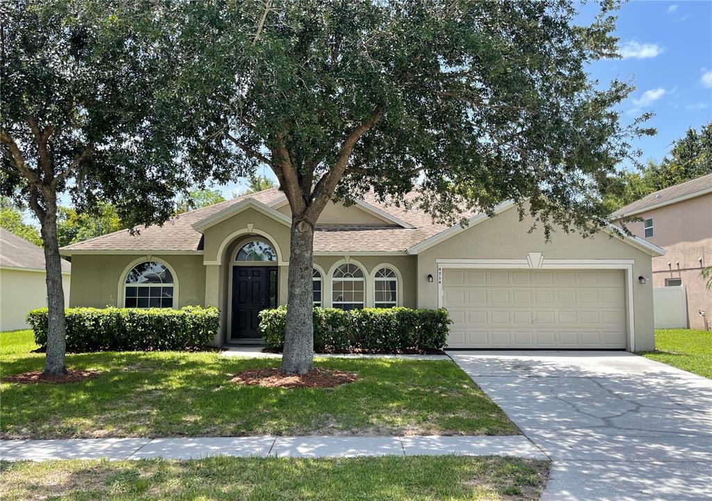 4714 Ashurst Street Kissimmee, FL 34758 - Photo 1 of 1 a front view of a house with a garden and trees