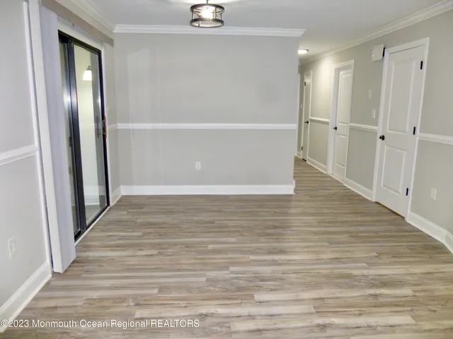 a view of an empty room with wooden floor and a bathroom