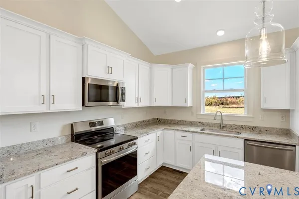 a kitchen with stainless steel appliances granite countertop white cabinets granite counter tops and a window