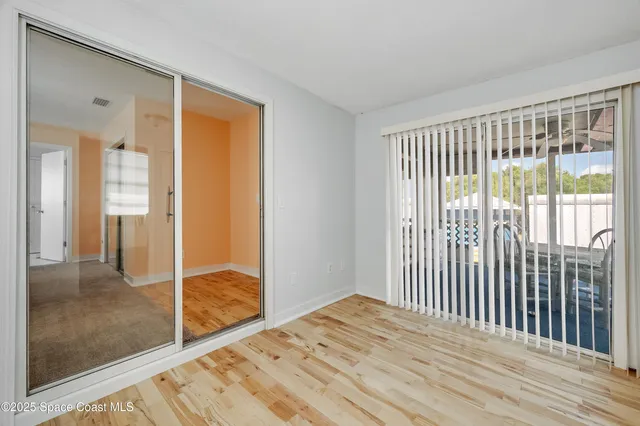 a view of a bedroom with wooden floor and windows