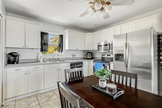 a kitchen with granite countertop stainless steel appliances a sink dishwasher a stove a refrigerator a dining table and chairs with wooden floor
