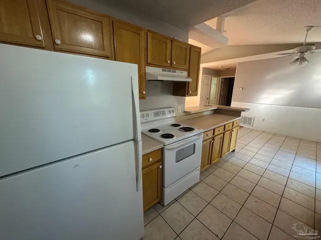 a kitchen with granite countertop a stove a sink and a refrigerator