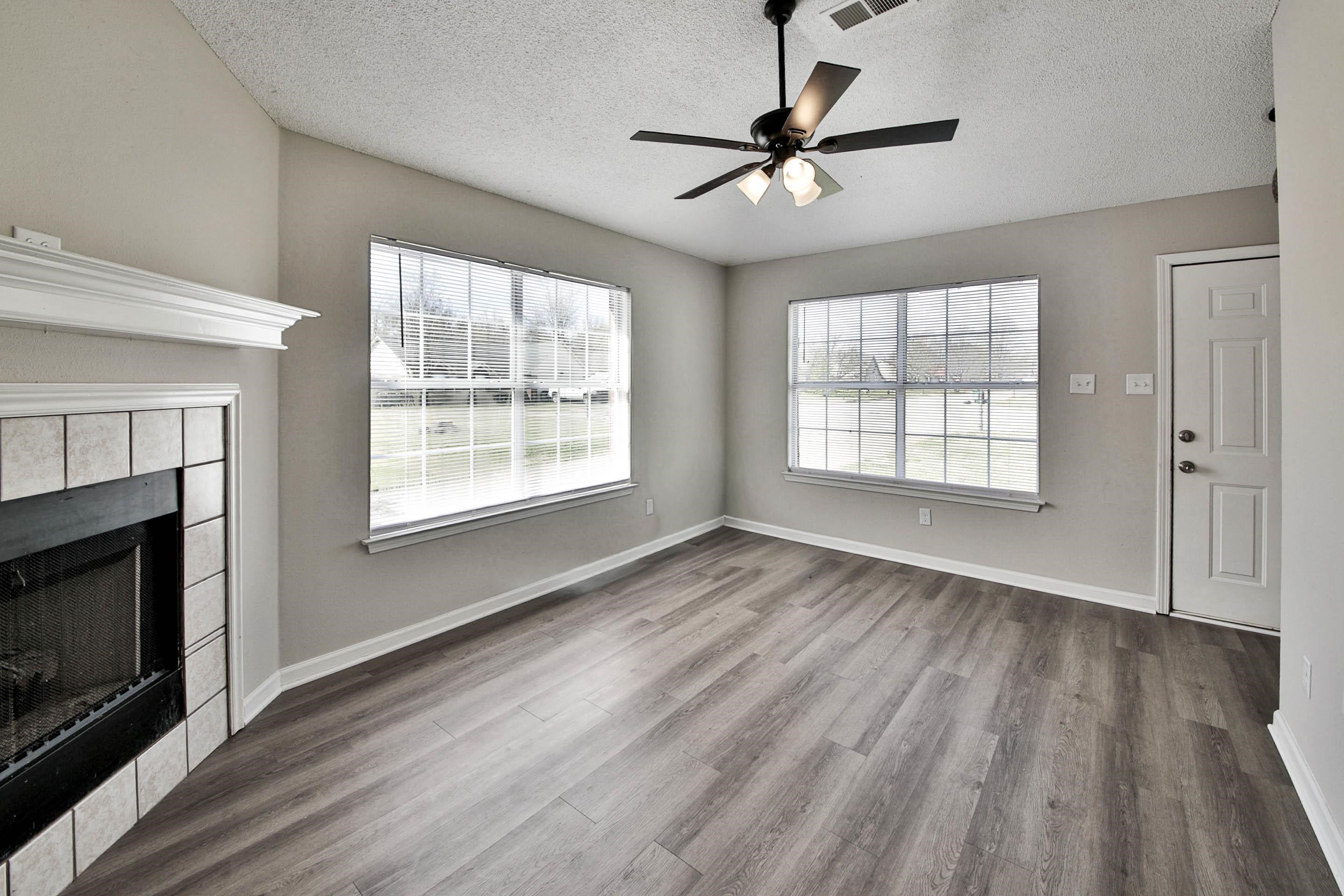 125 Pine Ridge Lane Oakland, TN 38060 - Photo 5 of 24 Unfurnished living room featuring ceiling fan, a tiled fireplace, wood finished floors, healthy amount of natural light, and a textured ceiling