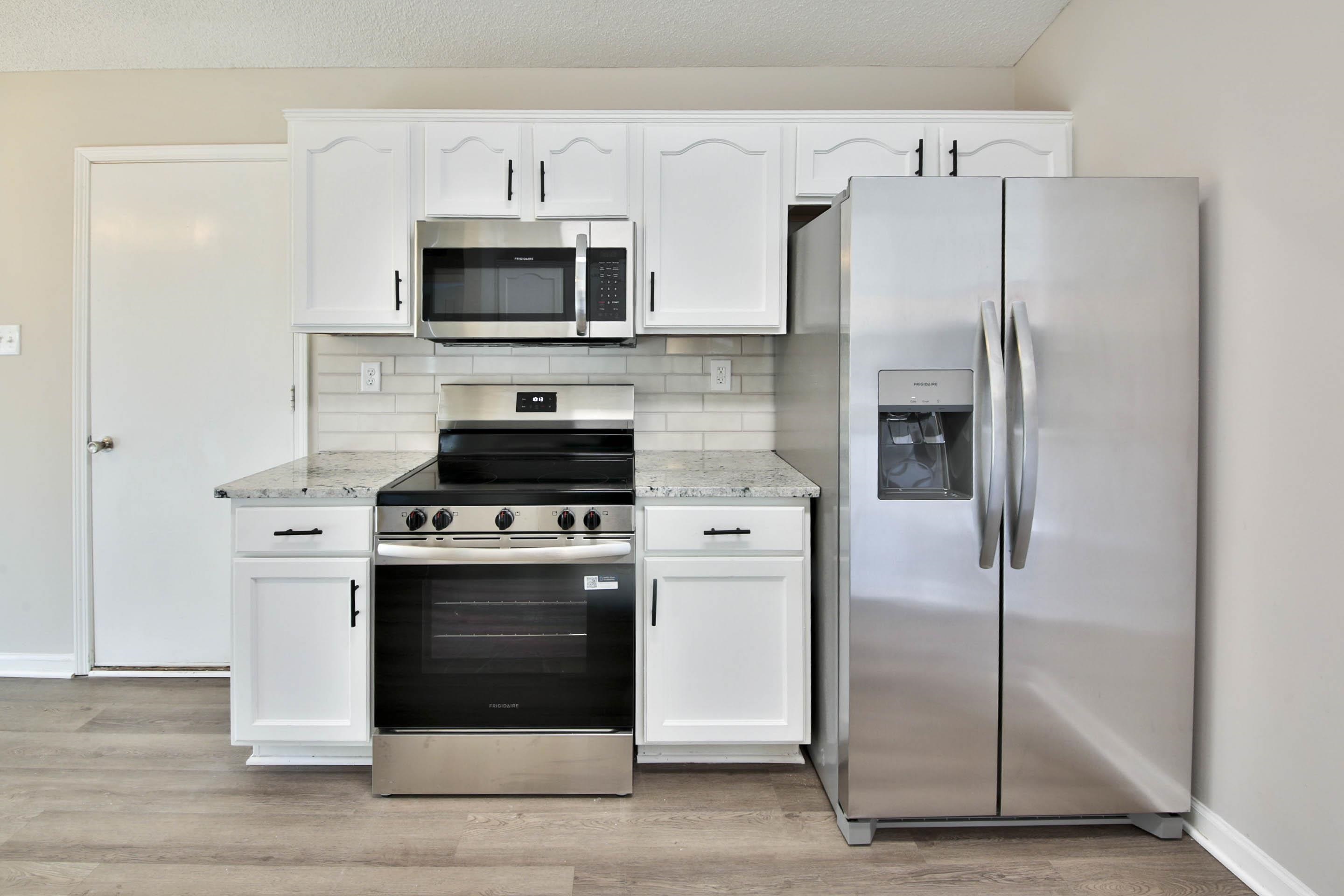 125 Pine Ridge Lane Oakland, TN 38060 - Photo 8 of 24 Kitchen featuring stainless steel appliances, white cabinetry, light stone counters, and light wood-type flooring